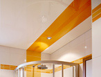 Ansicht eines weißen Badezimmers mit weißer Hochglanzdecke. Orange Streifen in Fliesen und Decke dienen als Gestaltungselemente.